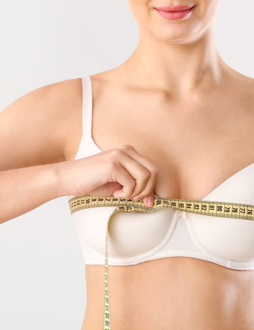 Young Woman Measuring Her Breast on White Background