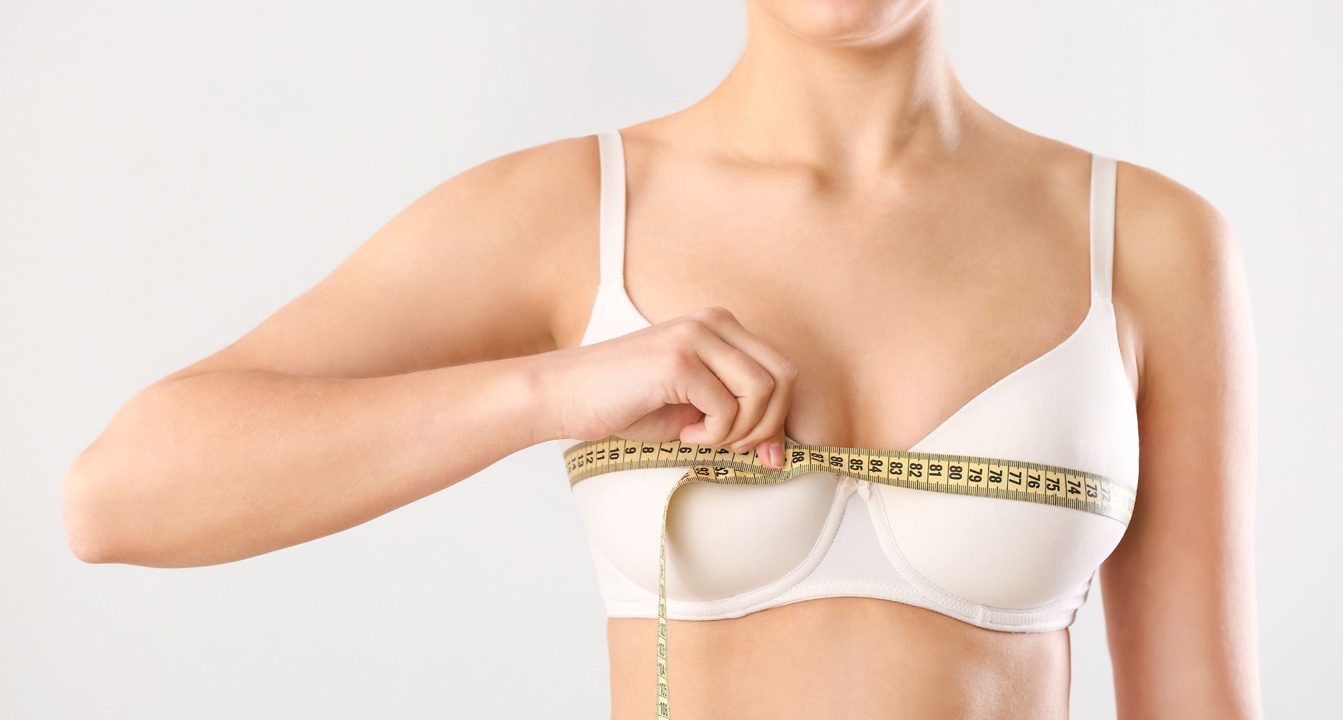 Young Woman Measuring Her Breast on White Background